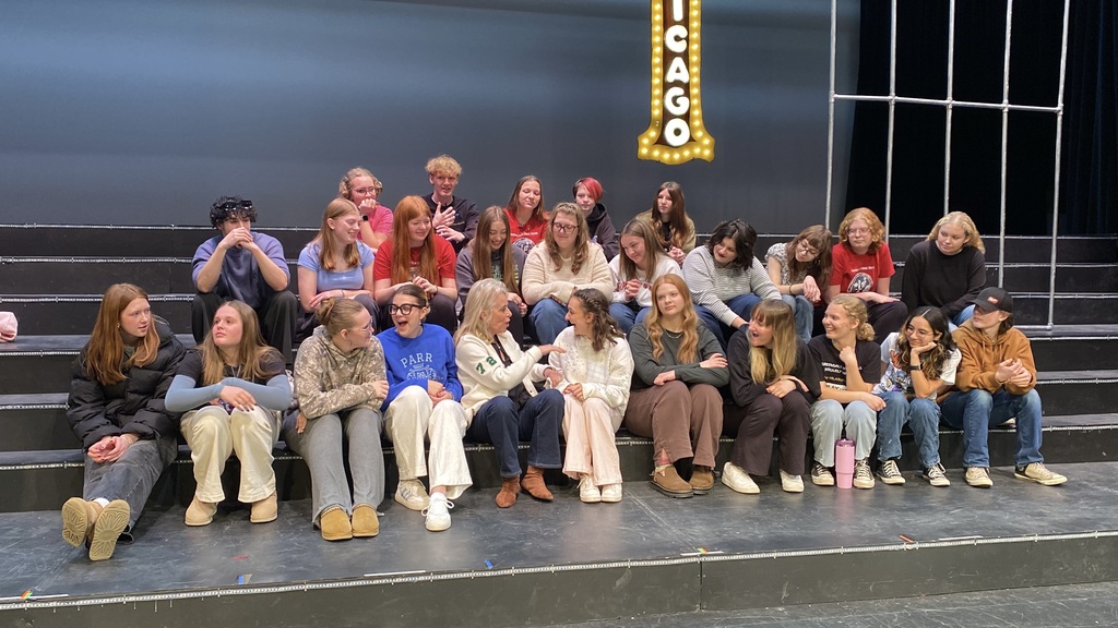 A group of people posing in front of a stage with a "CHICAGO" marquee sign.