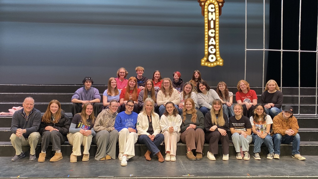 A group of people posing in front of a stage with a "CHICAGO" marquee sign.