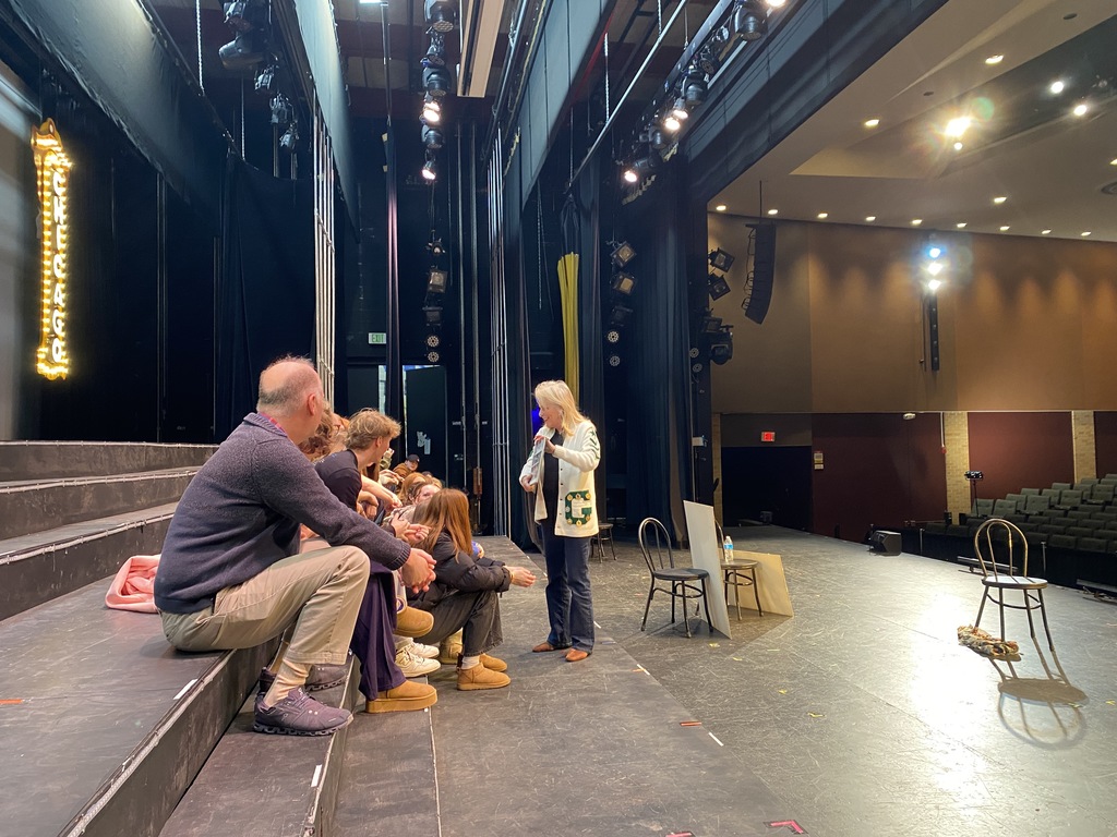 Group of people on a theater stage with "CHICAGO" sign.