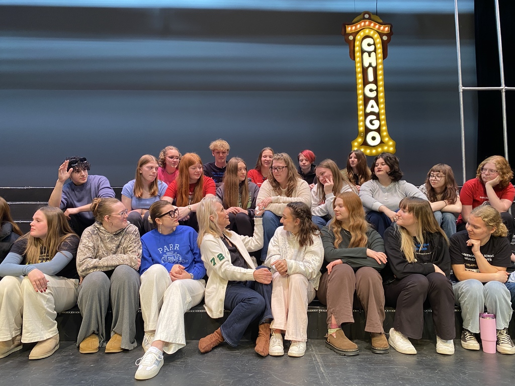 A group of people posing in front of a stage with a "CHICAGO" marquee sign.