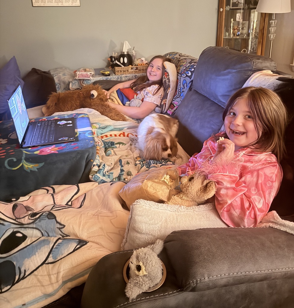 Two girls with popcorn watching a story told via Zoom.
