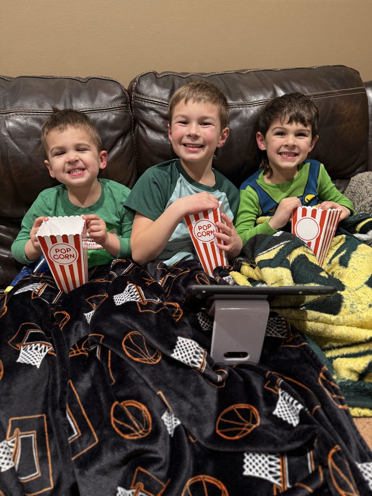 Three boys with popcorn watching a story told via Zoom.