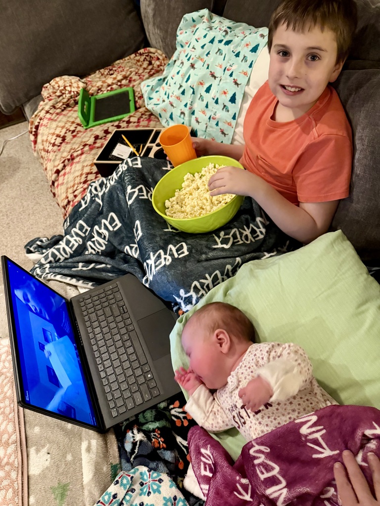 A boy and baby watching a story told via Zoom.