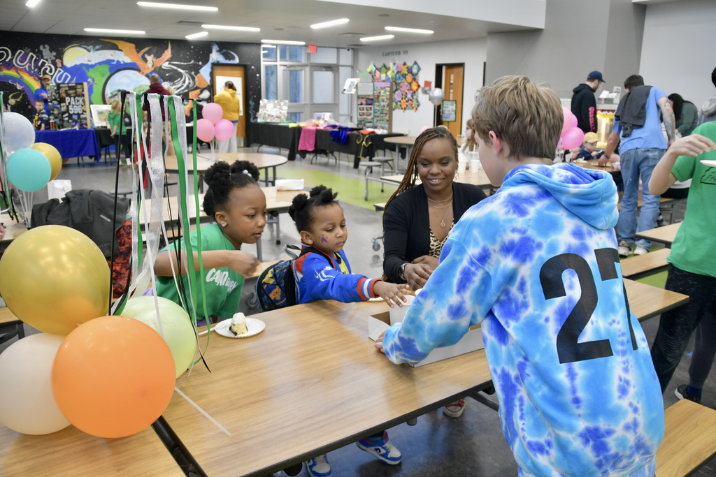 Family accepting cups of lemonade from a student volunteer at Jubilee Open House.