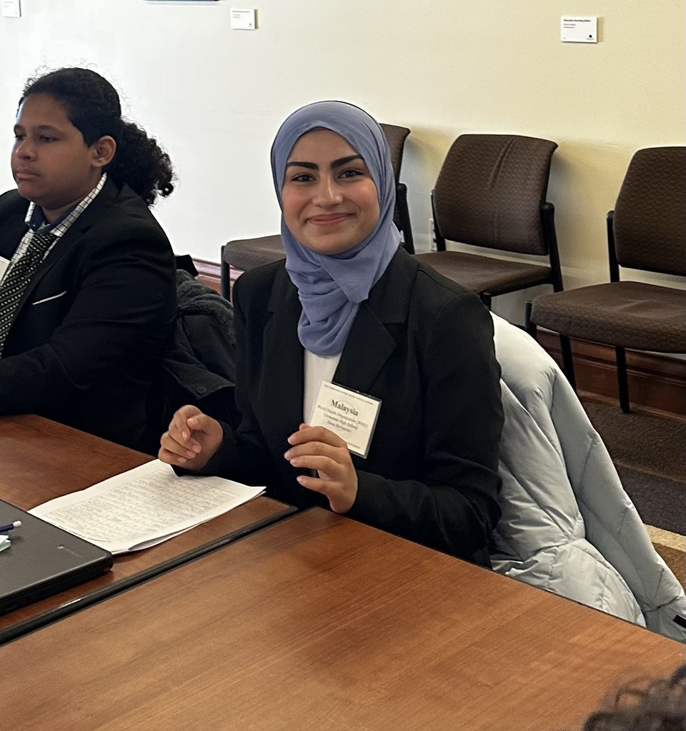 GHS student smiling while seated at a desk at Model UN conference.