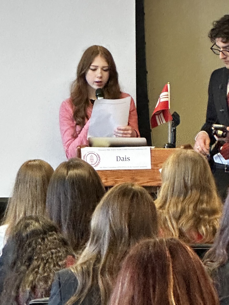 GHS students speaking at a podium at Model UN conference.