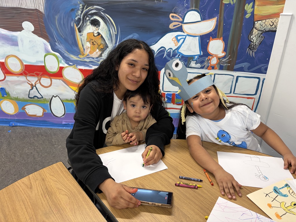 Pigeon Celebration: Caring adult with baby on lap, sitting and smiling with a 5K girl.