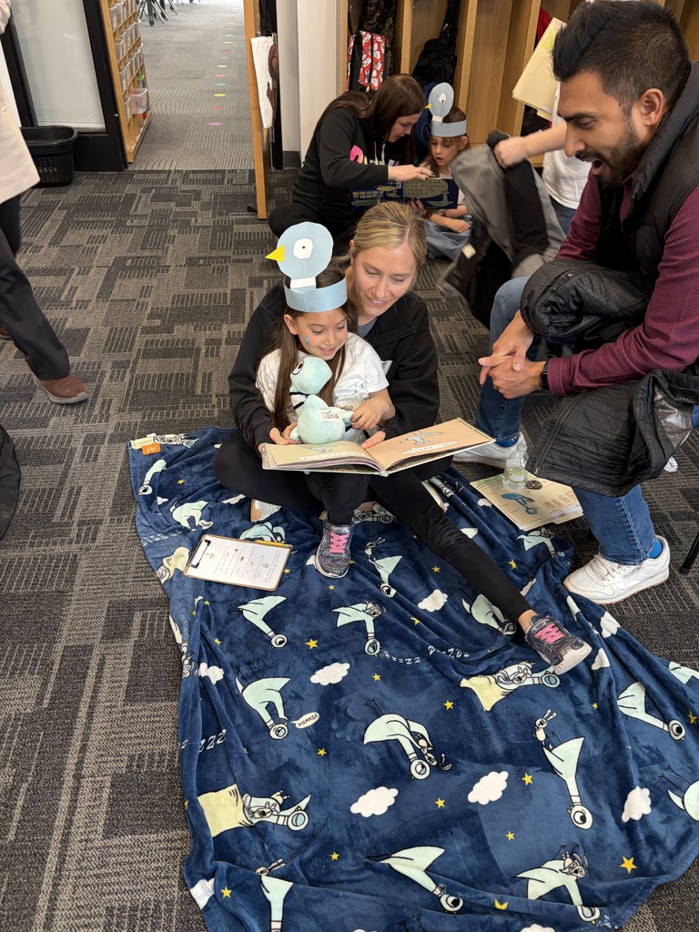 Pigeon Celebration: Two caring adults reading with 5K student on a pigeon blanket.