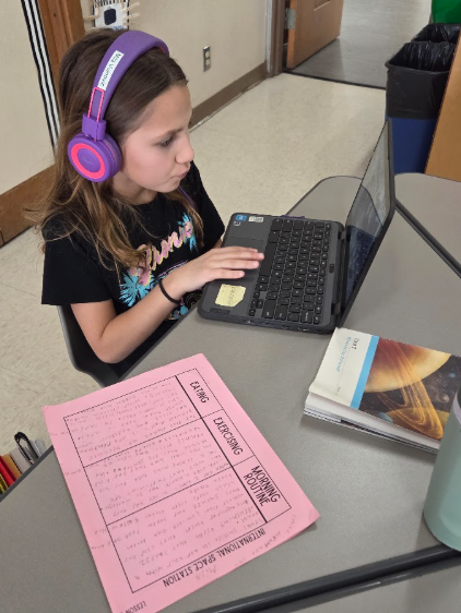 Astronomy: Third grade student doing research by reading and working on the computer.