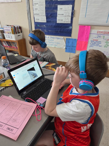 Astronomy: Two third grade students doing research by working on the computer.