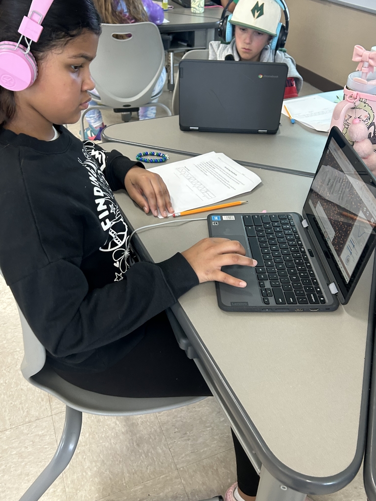 Student on laptop with others in the background researching how different animals communicate with each other.