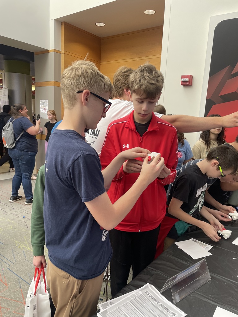 Two students standing together and working on a model car.