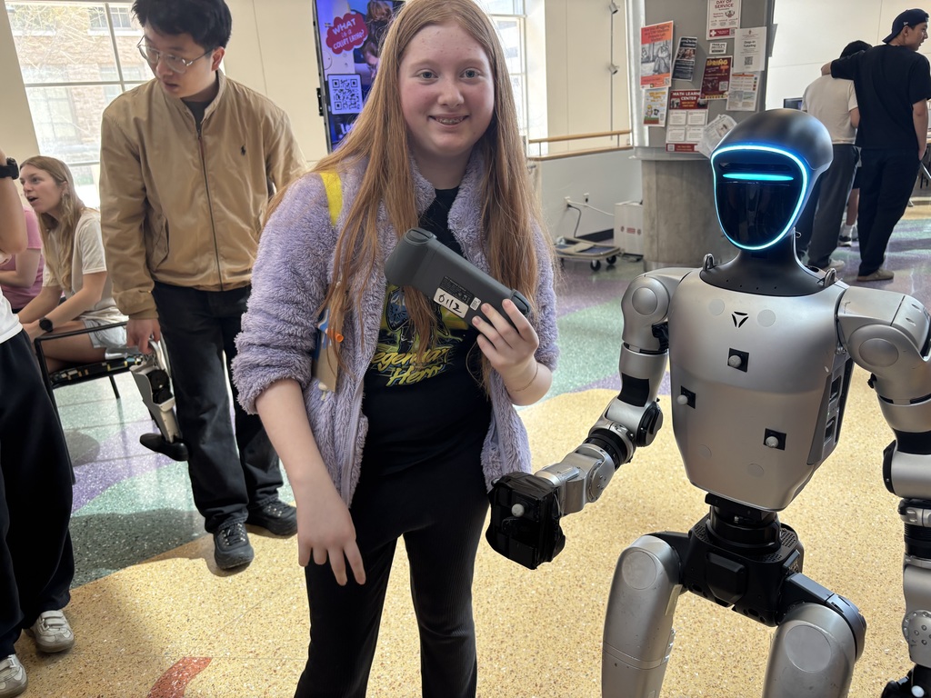 Student holding a control unit and operating a robot