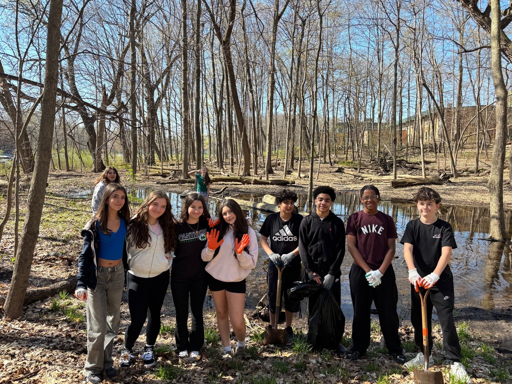 Group of 8th graders posing with shovels etc. during an Earth Day school woods & lawn clean up.