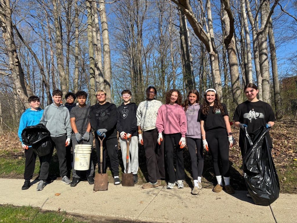 Group of 8th graders posing with trash bags etc. during an Earth Day school woods & lawn clean up.