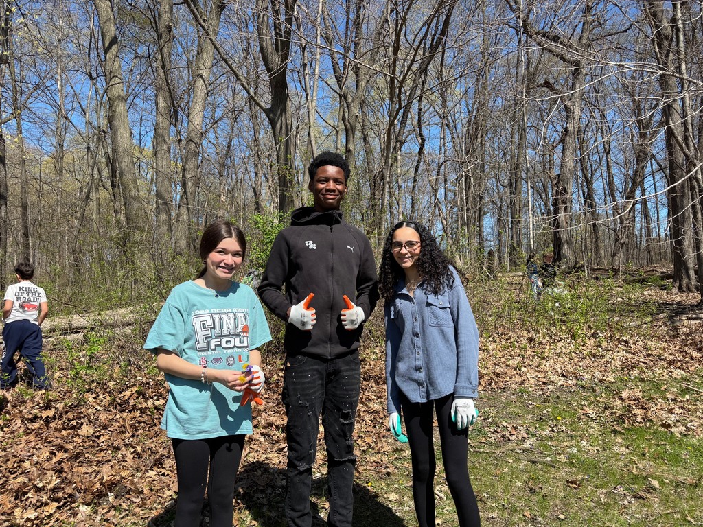Several 8th graders posing wearing work gloves as they cleaned the school woods and lawn in honor of Earth Day.