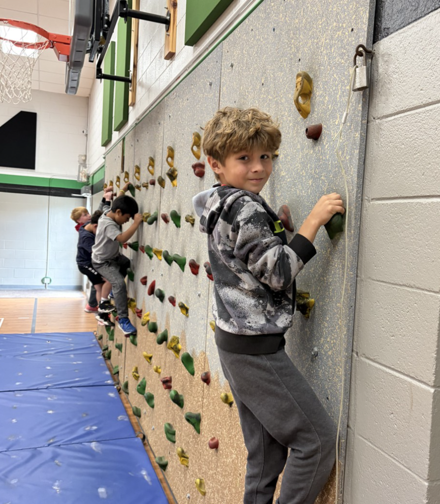 Four students climbing on the school's climbing wall in PE.
