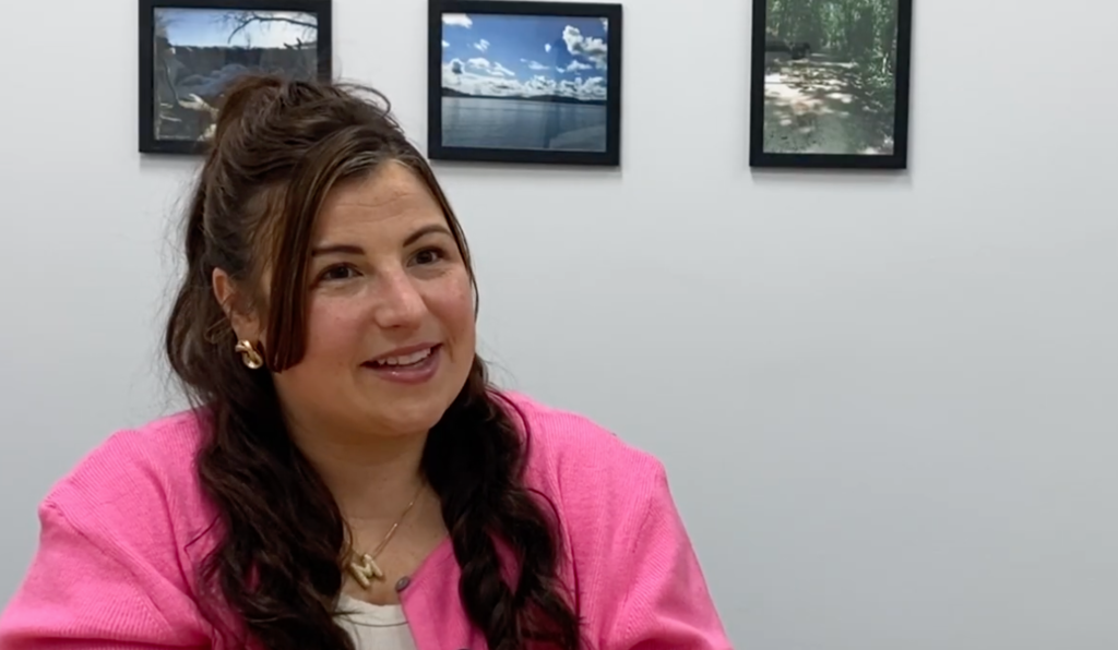 Person in a pink shirt smiling toward the camera.