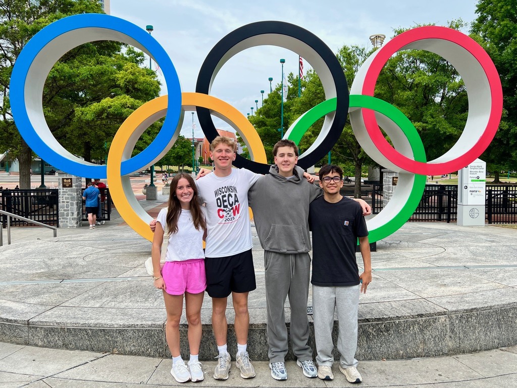Four students posing in front of the Olympic Rings.
