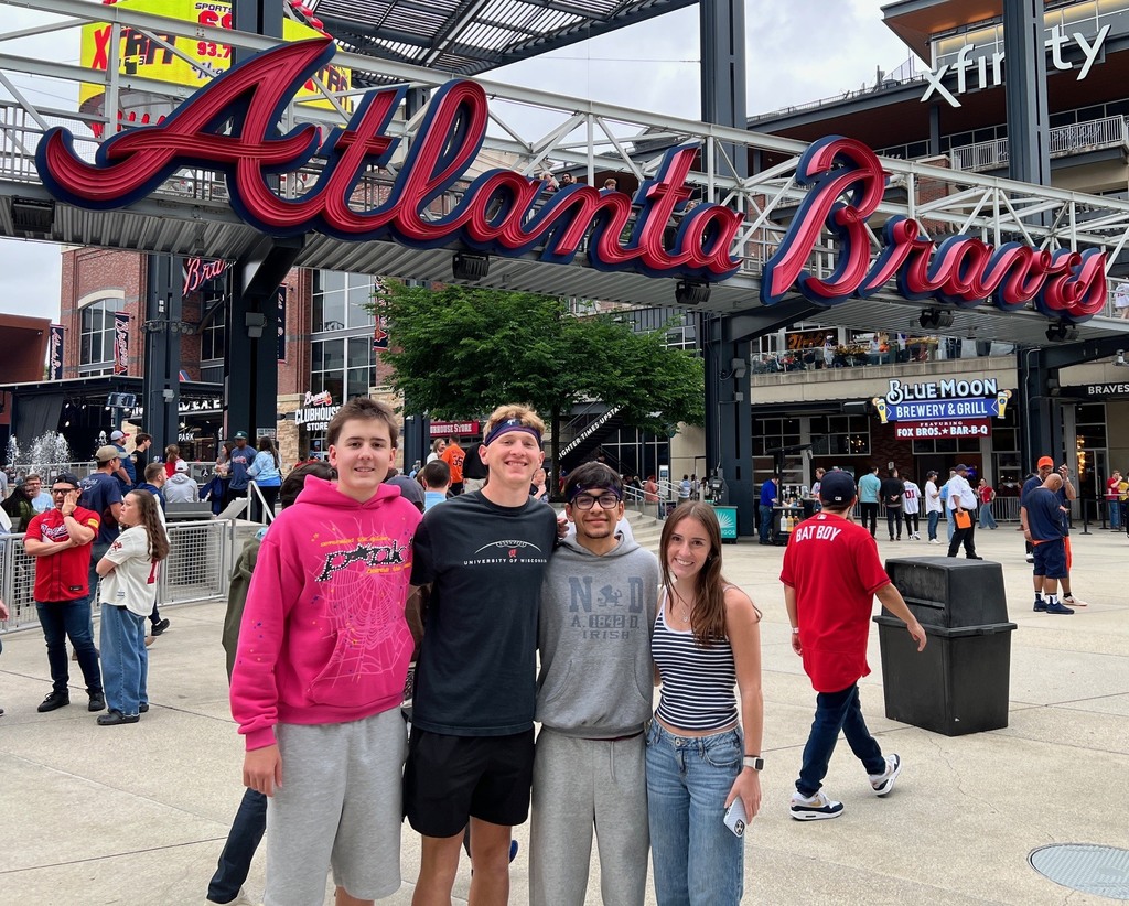 Four students posing together under an Atlanta Braves Arch.