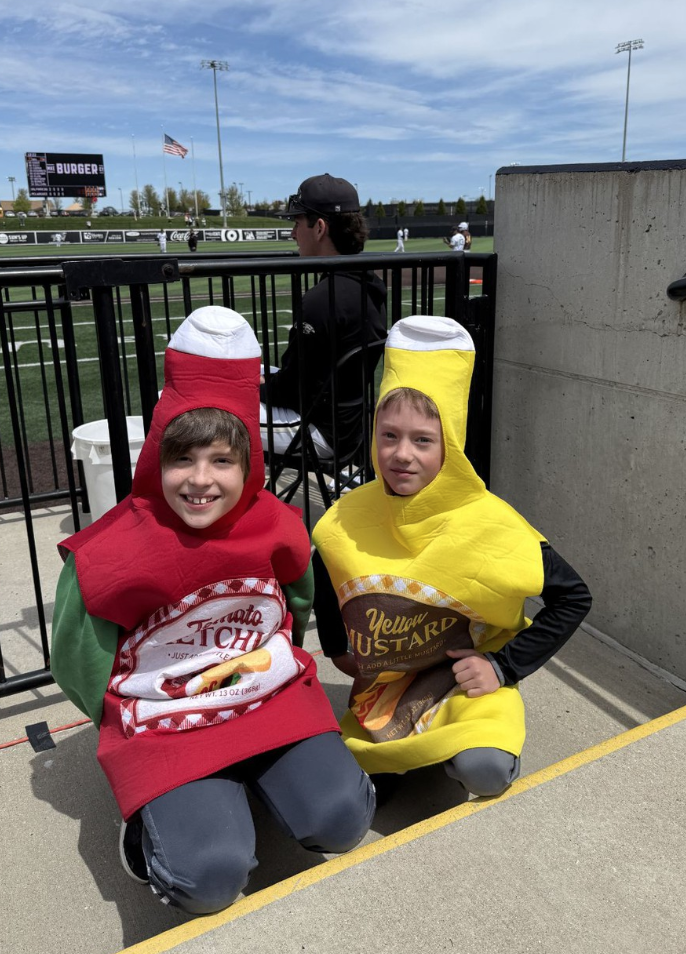 Two students dressed at ketchup and mustard at all-school baseball field trip.