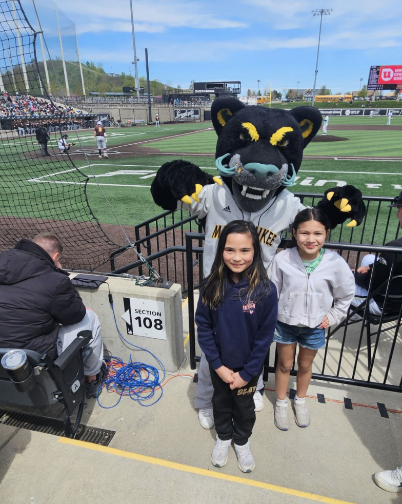 Two students posing with a mascot at the baseball field trip to Franklin Field.