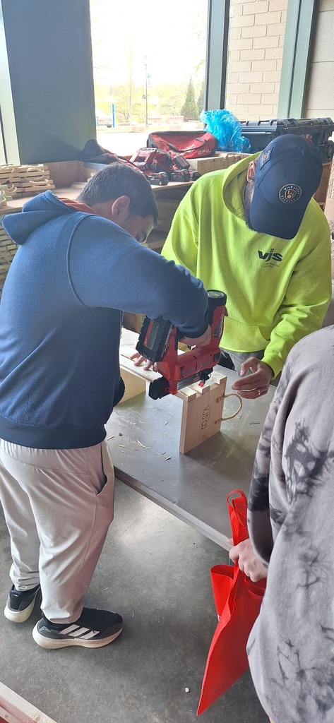 GHS student trying a power tool under supervision of an industry professional at career fair.