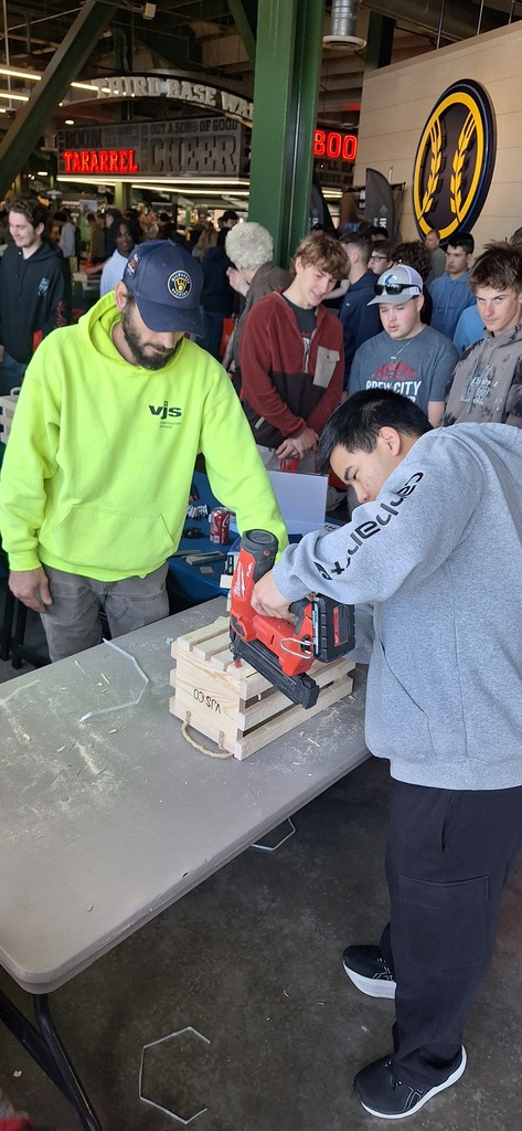 GHS student trying a power tool under supervision of an industry professional at career fair.