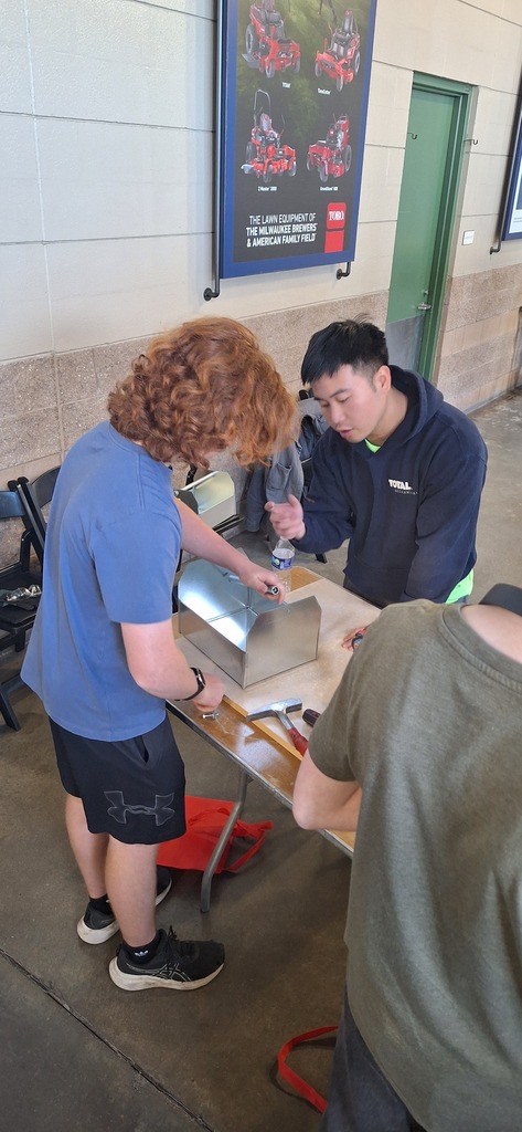 GHS student working with metal  under the supervision of a professional at a career fair.