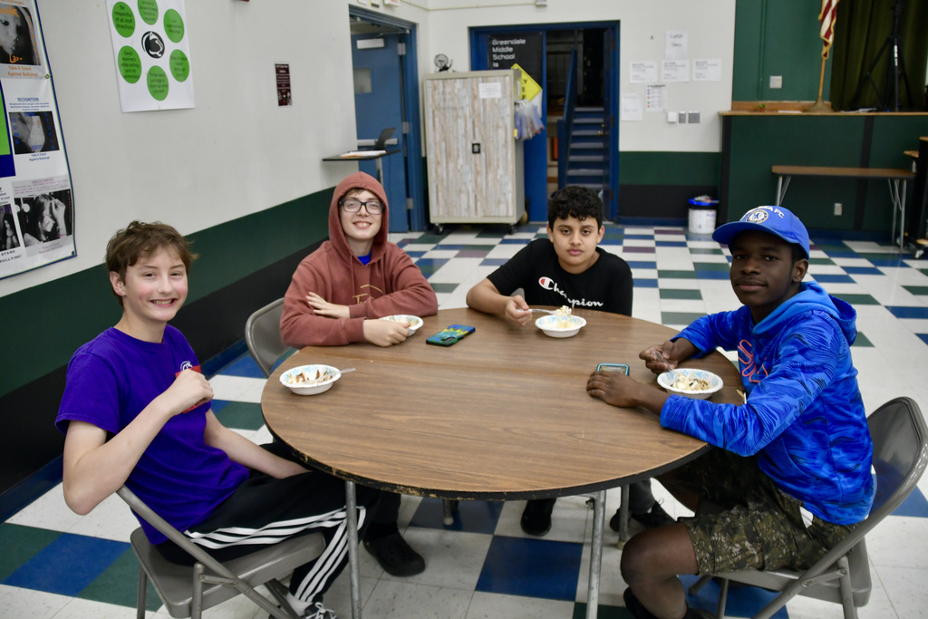 Four boys sitting at a table smiling and enjoying ice cream at Gallery Night.