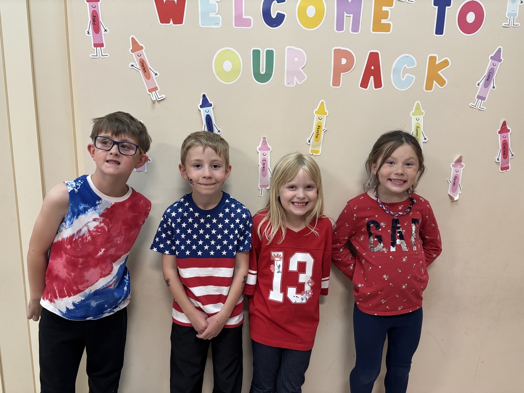 Four students smiling for the camera wearing red white and blue clothing