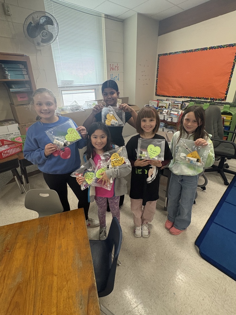 Students smiling at the camera while holding personal hygiene kits.
