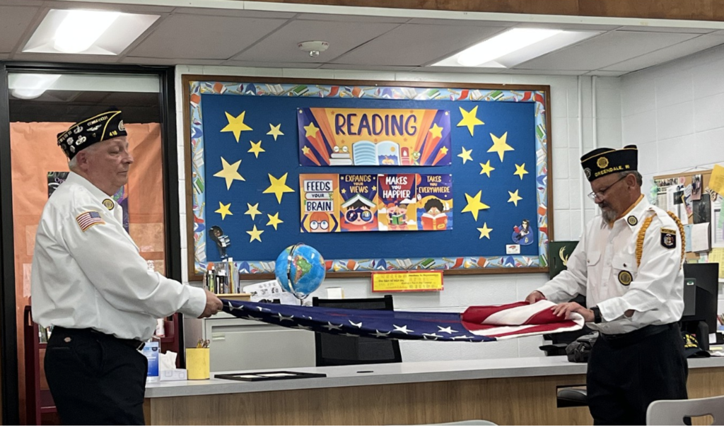 Two Veterans demonstrate how to fold the American flag.