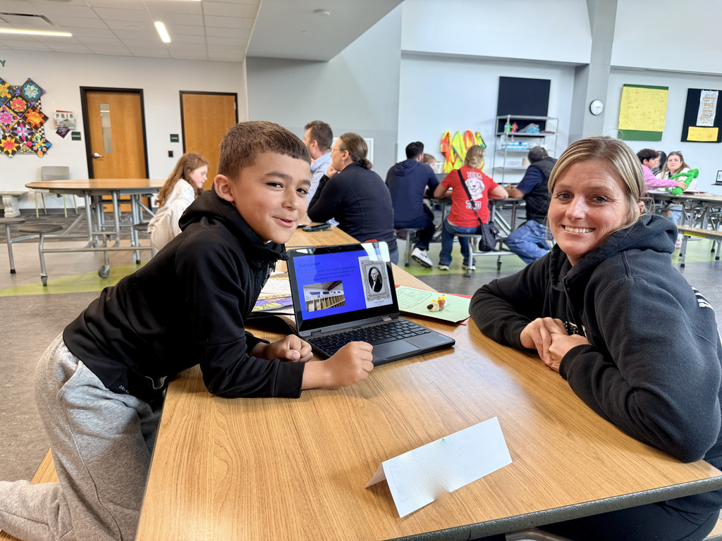 Student showing off the presentation of their school work to parent