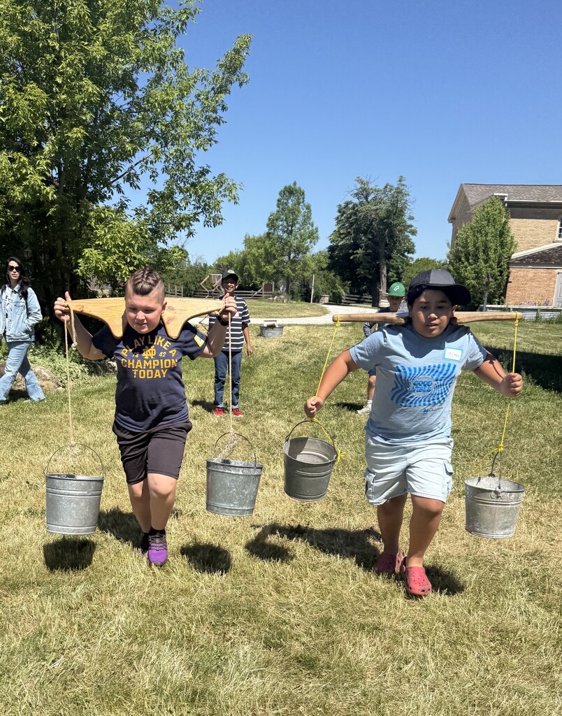 Two students carry buckets like in olden times at Trimborn Farm field trip.