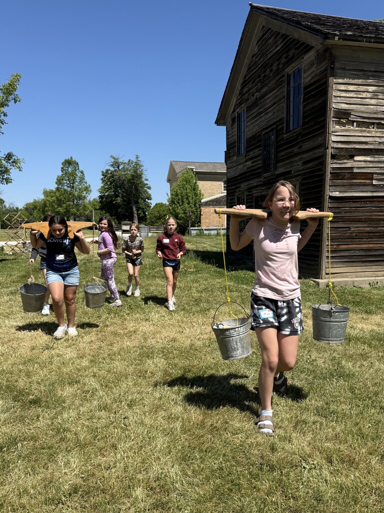 Students carrying buckets like in olden times at the Trimborn Farm field trip.