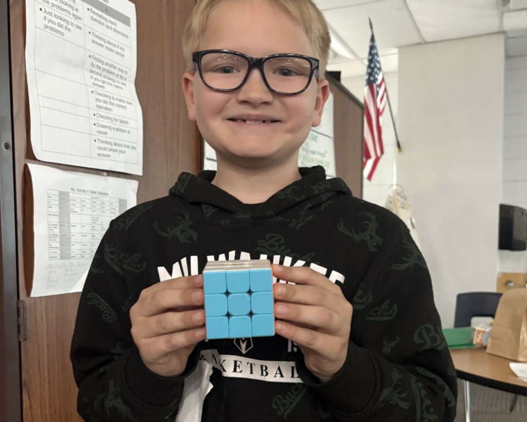 Smiling student shows off completed Rubik's Cube.