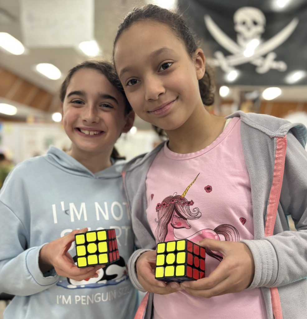 Smiling students show off their completed Rubik's Cubes.