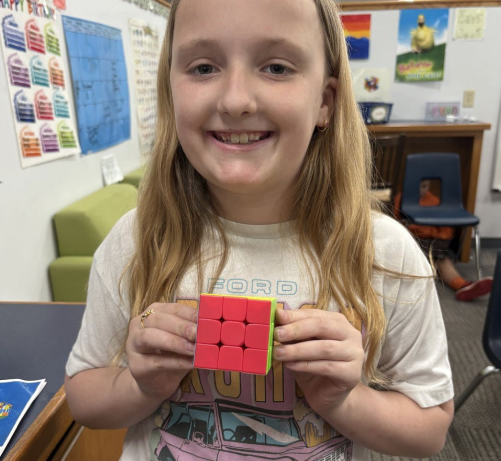 Smiling student shows off completed Rubik's Cube.