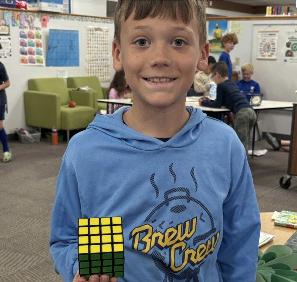 Smiling student shows off completed Rubik's Cube.