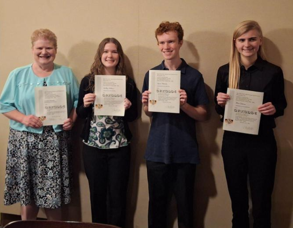 German students and their teacher smile and hold their award certificates.