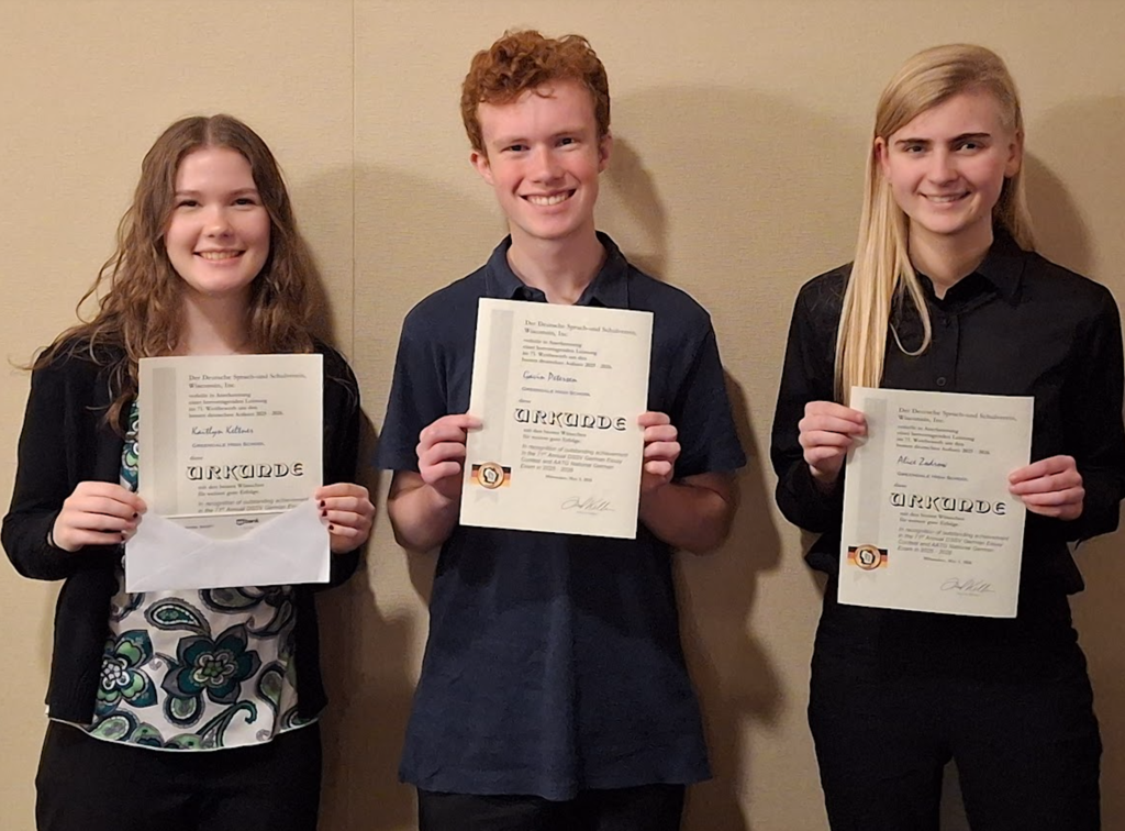 German students pose, smile and hold their award certificates.