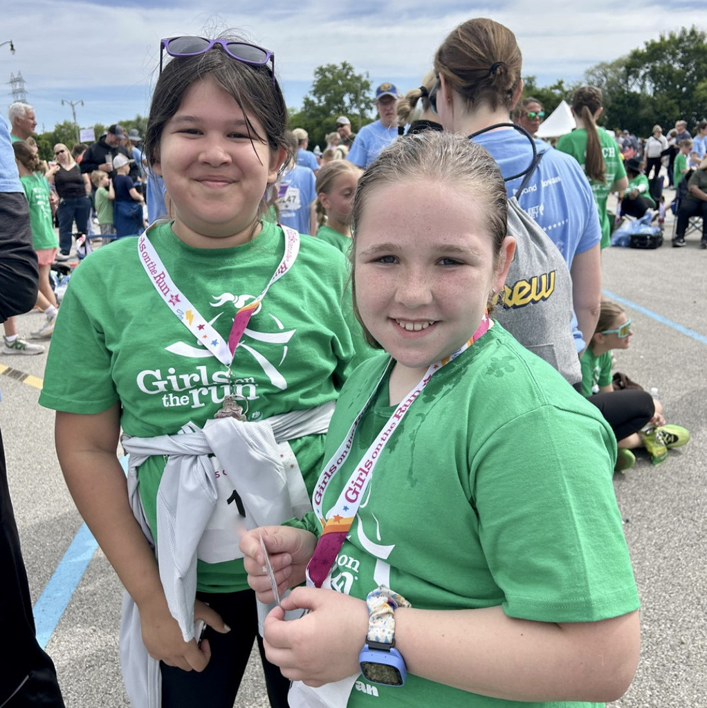 Two smiling College Park Girls on the Run members pose with their 5K run medals.