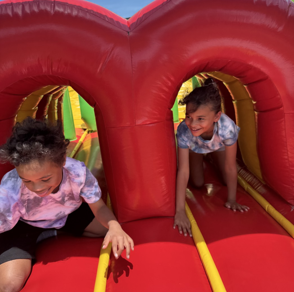 Two students crawling through a bouncy house at Olympic Day.