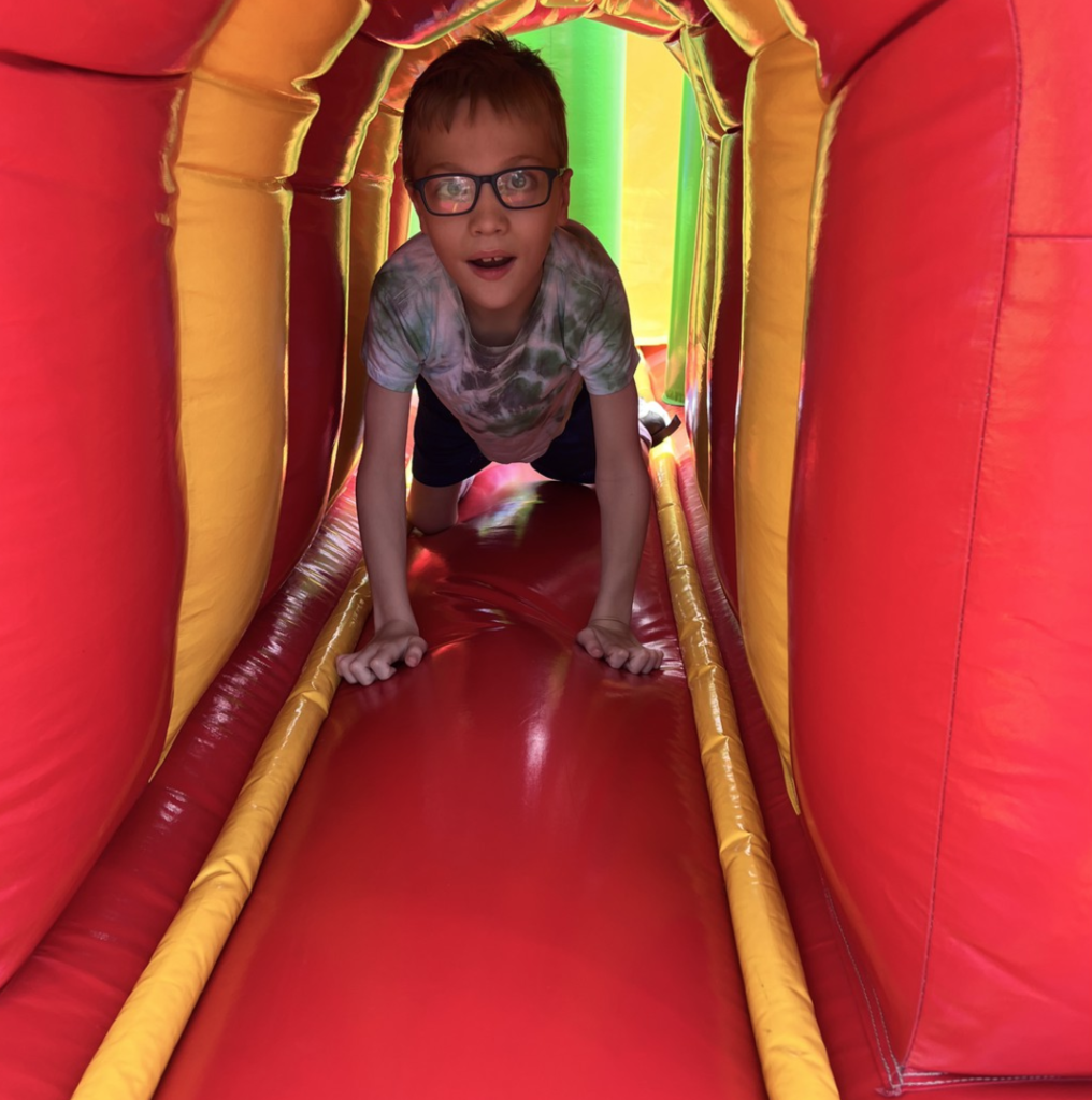 Student crawling through a bouncy house during Olympic Day.