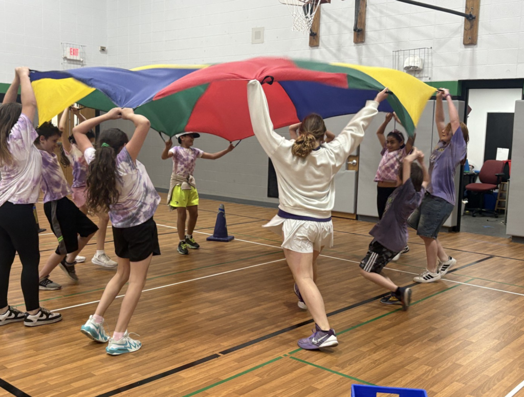Students holding a parachute over their heads during Olympic Day.