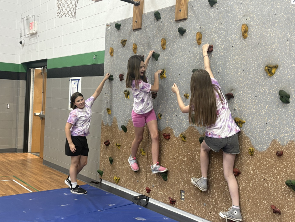Students climbing on the College Park Rock Wall in the school during Olympic Day.