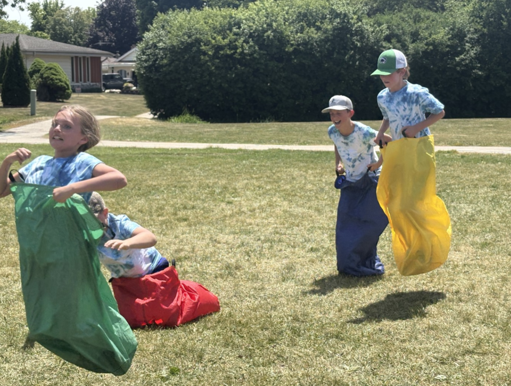 Students jumping enthusiastically in a sack race at Olympic Day.