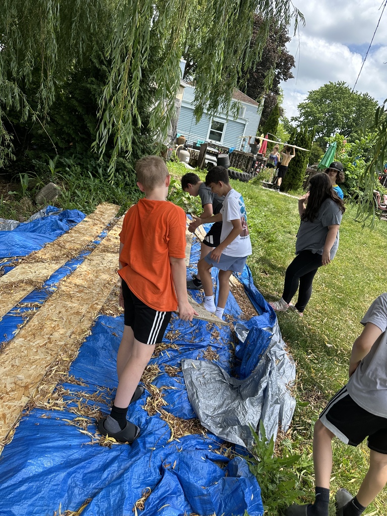 A team of students placing a tarp on an area of a yard.