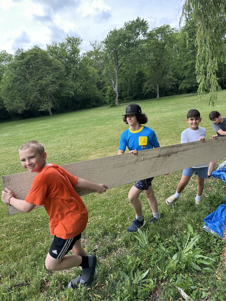 A team of students walking and working together to carry a long board.